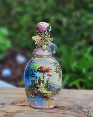 Bottle decorated with a woodland cottage scene beneath a jewelled topper
