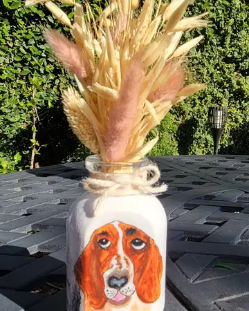 Cream vase painted with a face and topped with a spray of dried wheat