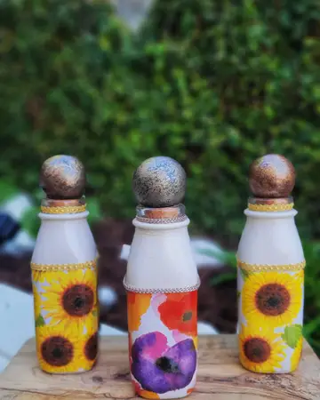 Three white bottles decorated with painted sunflowers