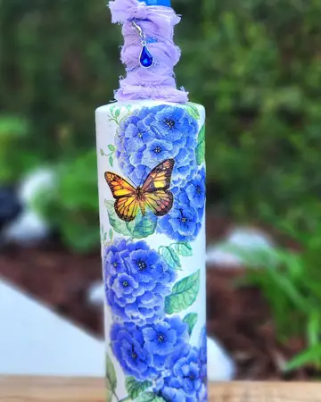 White bottle painted with blue roses and a butterfly