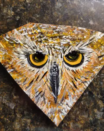 Hand-painted tile of an owl's face in gold and black