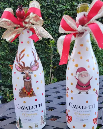 Two wine bottles decorated for the holidays with a stag and a Santa figure
