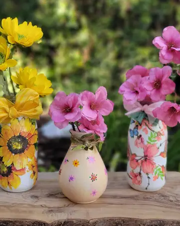 Small painted vases holding daisies and pink blossom