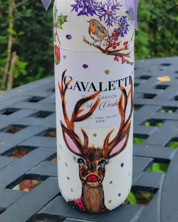 Wine bottle decorated with a painted stag and winter foliage