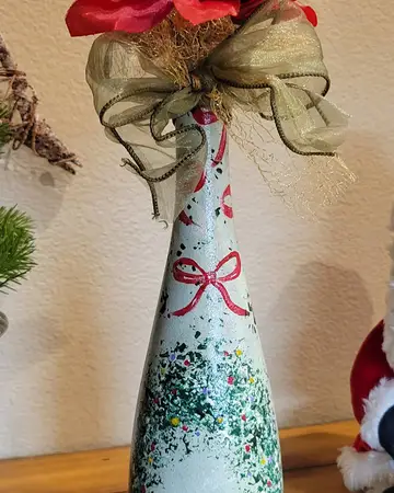 White bottle with painted trim and a wide gold ribbon