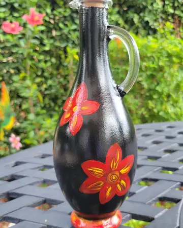 Black vase with a bold painted orange bloom